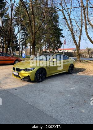 Eine vertikale Aufnahme eines modernen gelben BMW M4, der auf einem Parkplatz geparkt ist Stockfoto