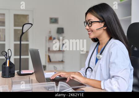 Seitenansicht eines jungen asiatischen Arztes, der online mit dem Patienten auf dem Laptop kommuniziert Stockfoto