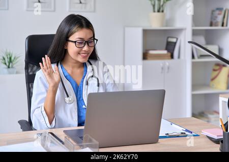 Junge asiatische Ärztin begrüßt den Patienten während einer Videokonferenz Stockfoto