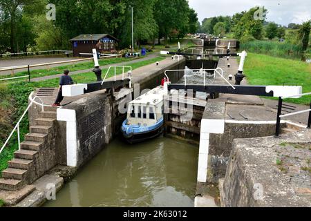 Kanal-Schmales Boot, das durch Schleusentore auf dem Weg den Flug von 21 Schleusen bei Hatton Schleusen auf dem Grand Union Canal, Warwick, Warwickshire, hinunterfährt Stockfoto