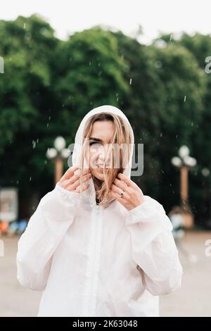 Nahaufnahme Porträt einer jungen Frau, die Regenmantel trägt, während sie am Regentag auf der Straße steht, und eines Blonde Mädchens, das in einem wasserdichten Mantel gekleidet ist Stockfoto