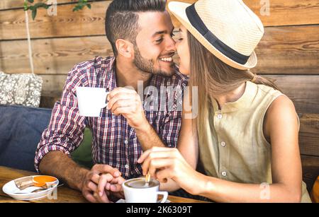 Junge Modeliebhaber pärchen zu Beginn der Liebesgeschichte - hübscher Mann küsst schöne Frau an der Café-Bar - Beziehungskonzept mit glücklichem Jungen