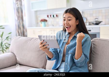 Aufgeregt asiatische Frau feiert Erfolg beim Blick auf digitale Tablet-Bildschirm Stockfoto