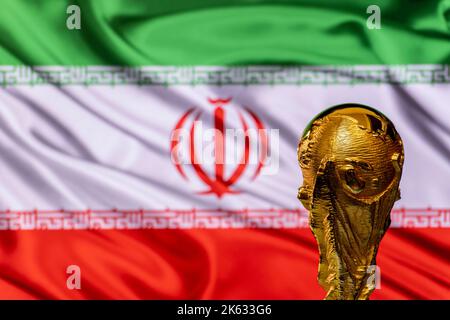 FIFA-WM-Trophäe vor dem Hintergrund der Iran-Flagge. Stockfoto