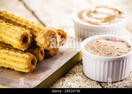 Churros, eine typische frittierte Süßspeise aus Brasilien, Mexiko und Spanien, hergestellt aus Weizenmehl und Wasser, in zylindrischer Form. Mit einer Schicht Zucker bestreut Stockfoto