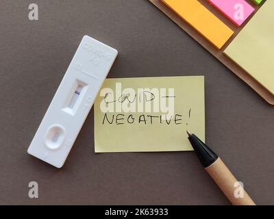 Negativer Covid-Test in der Hand, Nahaufnahme von Covid-negativer Beschriftung, Text auf Haftnotiz. Stockfoto
