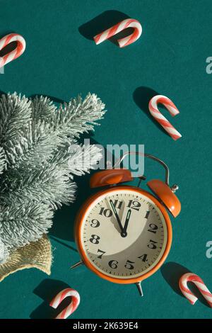 Countdown bis Mitternacht. Holzwecker mit Neujahr 2023. Einfache Fliese grünen Hintergrund mit Tannenzweigen und Zuckerrüben. Stockfoto