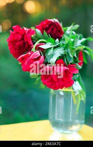 Bouquet von schönen rosa Pfingstrosen in einer Vintage-Glasvase auf einem Tisch Stockfoto