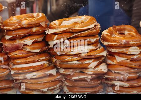 Auf dem Winterweihnachtsmarkt steht eine heiße, köstliche, frisch gebackene, weiche Brezel, gefüllt mit Schinken und Käse, auf der Theke. Perfekt für Oktoberfest oder Herbstfest. Tolle Snacks. Stockfoto