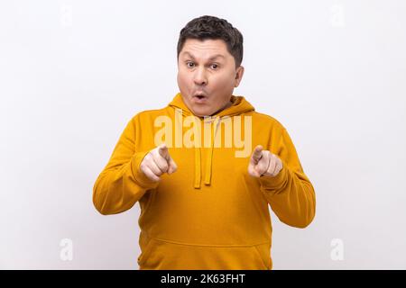 Portrait of Stauned man zeigt den Finger auf die Kamera und schaut mit schockiert staunenden Ausdruck, sehr überrascht über etwas, trägt Urban Style Hoodie. Innenaufnahme des Studios isoliert auf weißem Hintergrund. Stockfoto