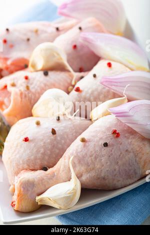 Rohe Hähnchenbeine mit Gemüse zum Kochen auf dem Küchentisch Stockfoto