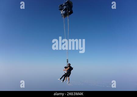 Dubai, Vereinigte Arabische Emirate: Zertifizierter Tandem-Tauchlehrer mit einem Anfänger, der über einen Gurt befestigt ist, setzt den Fallschirm in der Luft ein, um Widerstand zu erzeugen. Stockfoto