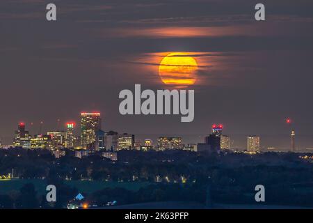 Halesowen, Großbritannien. 11.. Oktober 2022. Wetter in Großbritannien: Ein fast Vollmond steigt direkt über dem fast wolkenlosen Himmel des Stadtzentrums von Birmingham auf. Die hellen Lichter der Stadt werden von acht Meilen entfernt gesehen, wenn der orangefarbene Mond in einen klareren Himmel über der Stadt aufsteigt. Kredit: Lee Hudson/Alamy Live Nachrichten Stockfoto