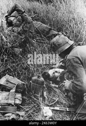Tote und verwundete anglokanadische Soldaten liegen während des Zweiten Weltkriegs auf dem Schlachtfeld in Orne, Normandie, Frankreich an der Westfront Stockfoto