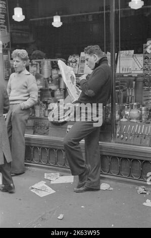 Straßenszene auf der 38. Street in der Nähe der 7. Avenue, New York City. Teenager lesen Zeitung. Datum: 1936. Nov Stockfoto