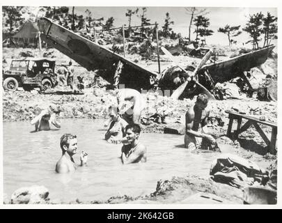 Vintage-Foto des Zweiten Weltkriegs - US-Marineinfanteristen schwimmen und waschen in einem Bombenloch Okinawa, Krieg gegen Japan, 1945 Stockfoto