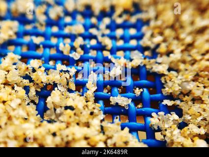 Eine Makroaufnahme von Sand auf einer blauen Sonnenbank Stockfoto