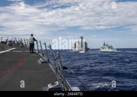 SÜDCHINESISCHES MEER (OKT 2, 2022) Arleigh Burke-Klasse Lenkraketen-Zerstörer USS Higgins (DDG 76), links, nähert sich Henry J. Kaiser-Klasse unterwegs Nachschuböler USNS Rappahannock (T-AO 204), Mitte, während er eine Nachschubflotte auf See mit der Royal Canadian Navy Halifax-Klasse Fregatte HMCS Windpeg (FFH 338) im Südchinesischen Meer, Oktober 2, durchführt. Higgins nimmt an multilateralen Übungen im Südchinesischen Meer zur Unterstützung des Indo-Pazifik-Einsatzes der japanischen Maritime Self-Defense Force zusammen mit der Royal Canadian Navy Teil. Routinemäßige multilaterale Übungen wie diese stärken die Interoperabilität Stockfoto