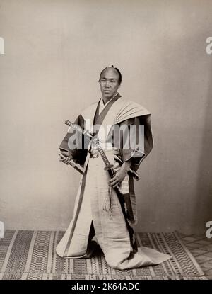 Vintage-Fotografie aus dem 19. Jahrhundert - Samurai mit zwei Schwertern in langen Hosen, Studio-Setting. Japan, um 1880. Wahrscheinlich von einem Schauspieler gestellt. Stockfoto