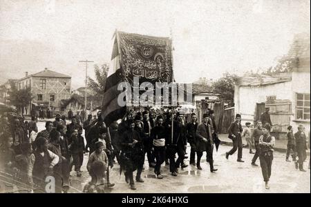 Patriotische türkische Märscher zu Beginn des Italienisch-Türkischen Krieges - mit einem Banner, geschmückt mit zwei koranischen Zitaten, die deutlich machen, dass es Gott ist, der den Sieg gewährt. Zwischen dem Königreich Italien und dem Osmanischen Reich wurde vom 29. September 1911 bis zum 18. Oktober 1912 der italienisch-türkische bzw. türkisch-italienische Krieg geführt. Als Folge dieses Konflikts hat Italien das osmanische Tripolitania Vilayet erobert, dessen wichtigste Unterprovinzen Fezzan, Cyrenaica und Tripolis selbst waren. Stockfoto