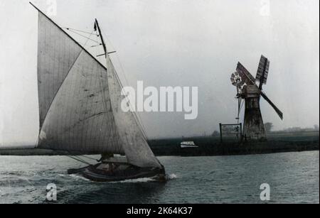 Ein Schild an der Windmühle weist auf den Weg zum Lion Hotel an der Thürne, Norfolk. Das Segelboot auf der Braut scheint sehr darauf bedacht zu sein, zum Abendessen nach Hause zu kommen! Stockfoto