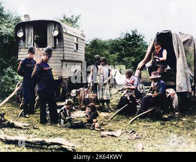 Zwei Polizisten sprechen mit einer Zigeunerfamilie bei ihrem Wohnwagen und Wagen auf Epsom Downs, Surrey, während des Epsom Derby. Stockfoto