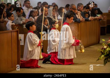 Auf den Knien nehmen multirassische Altarjungen an einer katholischen Messe in Tustin, CA, Teil. Stockfoto