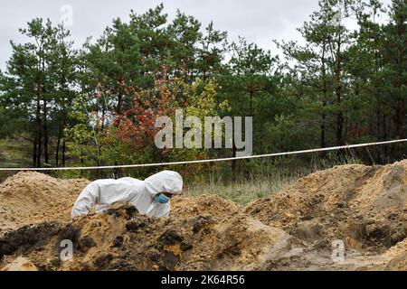 Lyman, Donezk, Ukraine. 11. Oktober 2022. Mitglied eines forensischen Teams bei der Arbeit während einer Exhumierung an einem Massengrab in Lyman. Als Teil einer schnellen ukrainischen Gegenoffensive, die Teile der Regionen Donezk, Charkiw und Cherson von der russischen Kontrolle zurück erobert hatte, wurde Lyman auch befreit. Die Zerstörung in Lyman, einem wichtigen Eisenbahn- und Transitzentrum, ist so weit verbreitet, dass große Teile der Stadt vollständig zerstört wurden. Kredit: ZUMA Press, Inc./Alamy Live Nachrichten Stockfoto