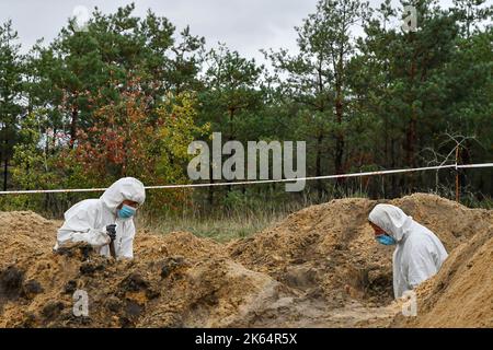 Lyman, Donezk, Ukraine. 11. Oktober 2022. Mitglieder eines forensischen Teams bei der Arbeit während einer Exhumierung an einem Massengrab in Lyman. Als Teil einer schnellen ukrainischen Gegenoffensive, die Teile der Regionen Donezk, Charkiw und Cherson von der russischen Kontrolle zurück erobert hatte, wurde Lyman auch befreit. Die Zerstörung in Lyman, einem wichtigen Eisenbahn- und Transitzentrum, ist so weit verbreitet, dass große Teile der Stadt vollständig zerstört wurden. Kredit: ZUMA Press, Inc./Alamy Live Nachrichten Stockfoto