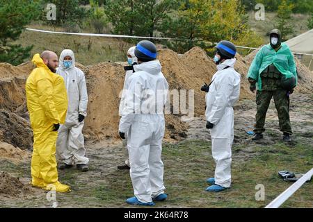 Lyman, Donezk, Ukraine. 11. Oktober 2022. Mitglieder eines forensischen Teams bei der Arbeit während einer Exhumierung an einem Massengrab in Lyman. Als Teil einer schnellen ukrainischen Gegenoffensive, die Teile der Regionen Donezk, Charkiw und Cherson von der russischen Kontrolle zurück erobert hatte, wurde Lyman auch befreit. Die Zerstörung in Lyman, einem wichtigen Eisenbahn- und Transitzentrum, ist so weit verbreitet, dass große Teile der Stadt vollständig zerstört wurden. Kredit: ZUMA Press, Inc./Alamy Live Nachrichten Stockfoto