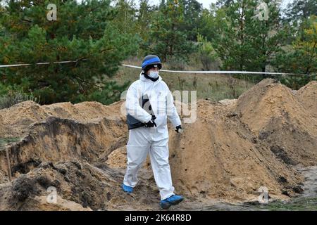 Lyman, Donezk, Ukraine. 11. Oktober 2022. Mitglied eines forensischen Teams bei der Arbeit während einer Exhumierung an einem Massengrab in Lyman. Als Teil einer schnellen ukrainischen Gegenoffensive, die Teile der Regionen Donezk, Charkiw und Cherson von der russischen Kontrolle zurück erobert hatte, wurde Lyman auch befreit. Die Zerstörung in Lyman, einem wichtigen Eisenbahn- und Transitzentrum, ist so weit verbreitet, dass große Teile der Stadt vollständig zerstört wurden. Kredit: ZUMA Press, Inc./Alamy Live Nachrichten Stockfoto