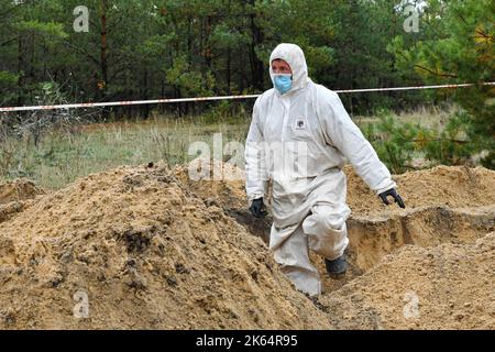 Lyman, Donezk, Ukraine. 11. Oktober 2022. Mitglied eines forensischen Teams bei der Arbeit während einer Exhumierung an einem Massengrab in Lyman. Als Teil einer schnellen ukrainischen Gegenoffensive, die Teile der Regionen Donezk, Charkiw und Cherson von der russischen Kontrolle zurück erobert hatte, wurde Lyman auch befreit. Die Zerstörung in Lyman, einem wichtigen Eisenbahn- und Transitzentrum, ist so weit verbreitet, dass große Teile der Stadt vollständig zerstört wurden. Kredit: ZUMA Press, Inc./Alamy Live Nachrichten Stockfoto