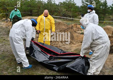 Lyman, Donezk, Ukraine. 11. Oktober 2022. Mitglieder eines forensischen Teams bei der Arbeit während einer Exhumierung an einem Massengrab in Lyman. Als Teil einer schnellen ukrainischen Gegenoffensive, die Teile der Regionen Donezk, Charkiw und Cherson von der russischen Kontrolle zurück erobert hatte, wurde Lyman auch befreit. Die Zerstörung in Lyman, einem wichtigen Eisenbahn- und Transitzentrum, ist so weit verbreitet, dass große Teile der Stadt vollständig zerstört wurden. Kredit: ZUMA Press, Inc./Alamy Live Nachrichten Stockfoto