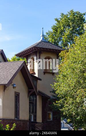 Blick nach oben auf einen Kirchturm im spanischen Stil des frühen 20.. Jahrhunderts und einen Glockenturm mit Stuckwand und Bogenfenstern Stockfoto