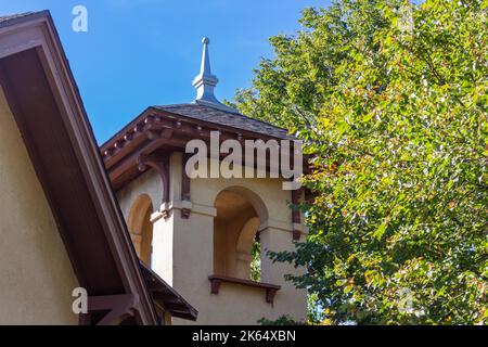 Blick nach oben auf einen Kirchturm im spanischen Stil des frühen 20.. Jahrhunderts und einen Glockenturm mit Stuckwand und Bogenfenstern Stockfoto