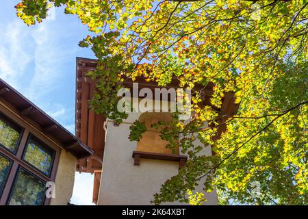 Blick nach oben auf einen Kirchturm im spanischen Stil des frühen 20.. Jahrhunderts und einen Glockenturm mit Stuckwand und Bogenfenstern Stockfoto