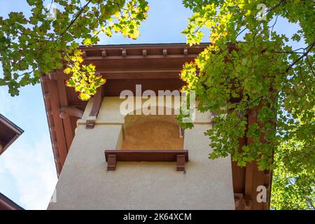 Blick nach oben auf einen Kirchturm im spanischen Stil des frühen 20.. Jahrhunderts und einen Glockenturm mit Stuckwand und Bogenfenstern Stockfoto