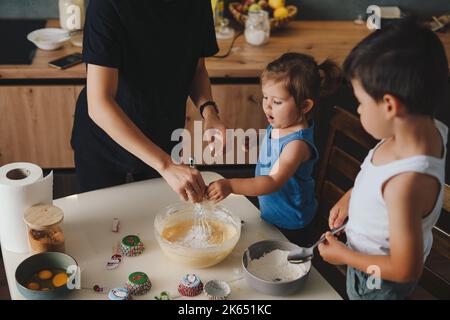 Glückliche Familie in der Küche, die den Teig zubereitet, Kekse backen. Familie mit Kind verbringt morgens Zeit in der Küche. Stockfoto