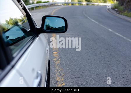 Weißes Auto ist auf der Seite einer asphaltierten Straße geparkt Stockfoto