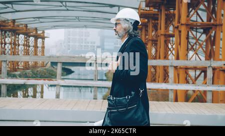 Selbstbewusster reifer Mann Investor arbeitet in Baustellen Holding Blueprint . Menschen- und Geschäftskonzept. Stockfoto