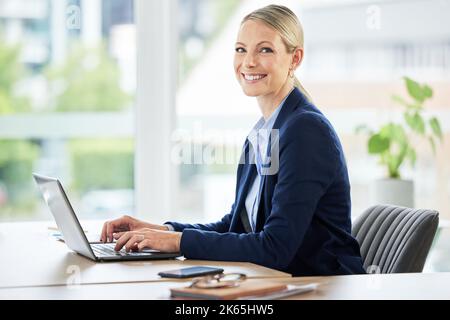 Kaukasische Geschäftsfrau, die an ihrem Laptop arbeitet. Porträt eines jungen asiatischen Geschäftsmannes, der in einem modernen Büro arbeitet. Glückliche Geschäftsfrau tippt auf sie Stockfoto