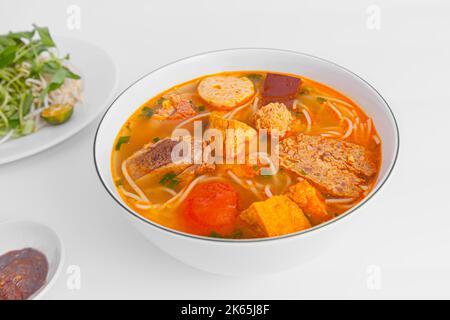 Bun Rieu Cua, Krabbenpaste Vermicelli-Suppe mit gehackten Garnelen, Tofu, Tomaten, Garnelenpaste, vietnamesisches Essen auf weißem Hintergrund isoliert, Nahaufnahme Stockfoto