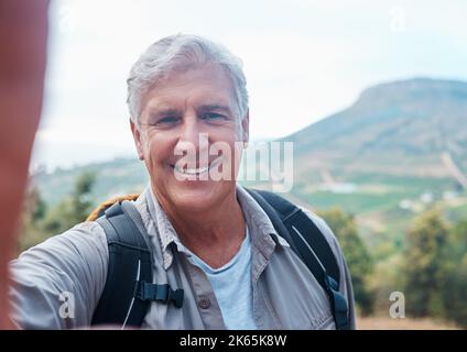 Wandern ist gut für die Seele. Ein älterer Mann, der ein Selfie macht, während er unterwegs ist. Stockfoto