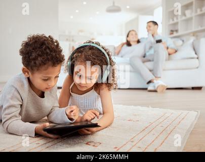 Entdecken Sie die Online-Welt. Ein kleiner Bruder und eine kleine Schwester benutzen ein digitales Tablet zu Hause. Stockfoto