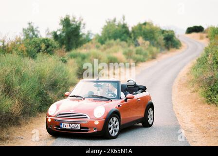 Der Bräutigam beugte seinen Kopf vor dem Kopf der Braut und saß in einem Cabrio auf der Straße Stockfoto