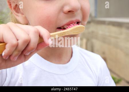 Ein Kind putzt seine Zähne mit einer hölzernen Zahnbürste. Stockfoto