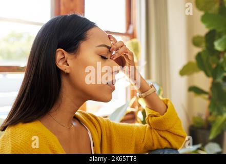 Gestresste Frau, Kopfschmerzen und Burnout mit psychischen Problemen zu Hause im Wohnzimmer. Weiblich in Depression allein mit Kopf Gefühl ängstlich Stockfoto