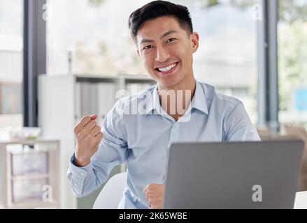 Porträt eines lächelnden asiatischen Geschäftsmannes, aufgeregt und erfolgreich, während er eine Faust als gewinnende Geste macht. Glücklich schöner Mann feiern Erfolg Stockfoto