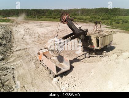 Schaufelbagger belädt im Sommer LKW mit Kreide im Steinbruch Stockfoto