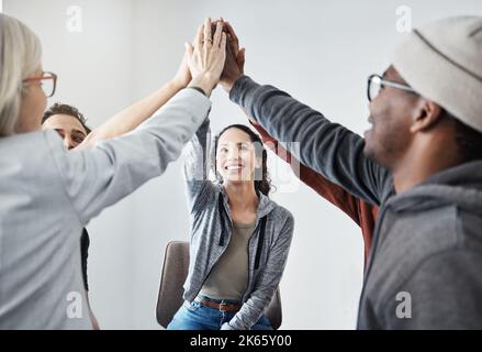 Fröhliche, vielfältige Gruppe von Geschäftsleuten, die lächeln und sich bei einer Besprechung in einem Büro bei der Arbeit mit fünf Gästen treffen. Glückliche Frauen und Männer kommen dazu Stockfoto